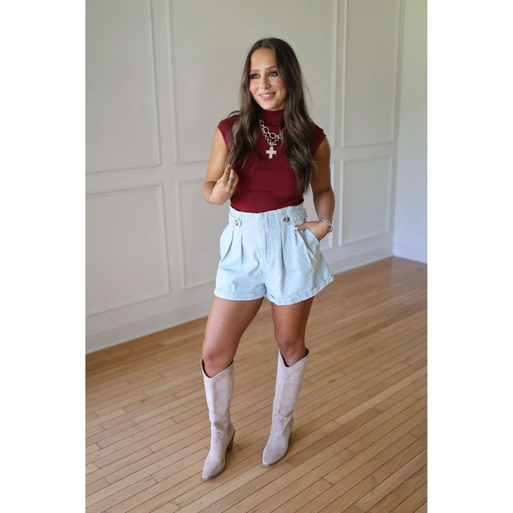 Woman wearing a red top, light blue shorts