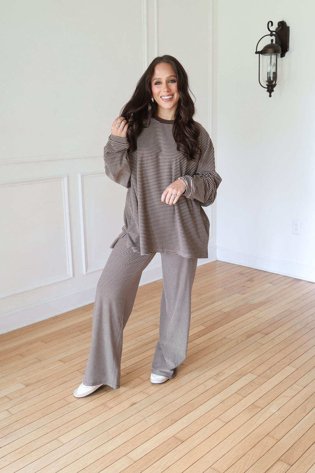 A woman modeling a matching two-piece lounge set consisting of a long-sleeve waffle-knit top and wide-leg pants in a taupe-brown color