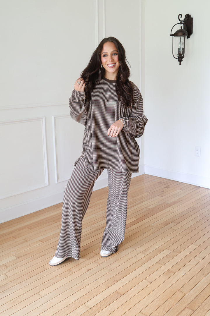 A woman modeling a matching two-piece lounge set consisting of a long-sleeve waffle-knit top and wide-leg pants in a taupe-brown color