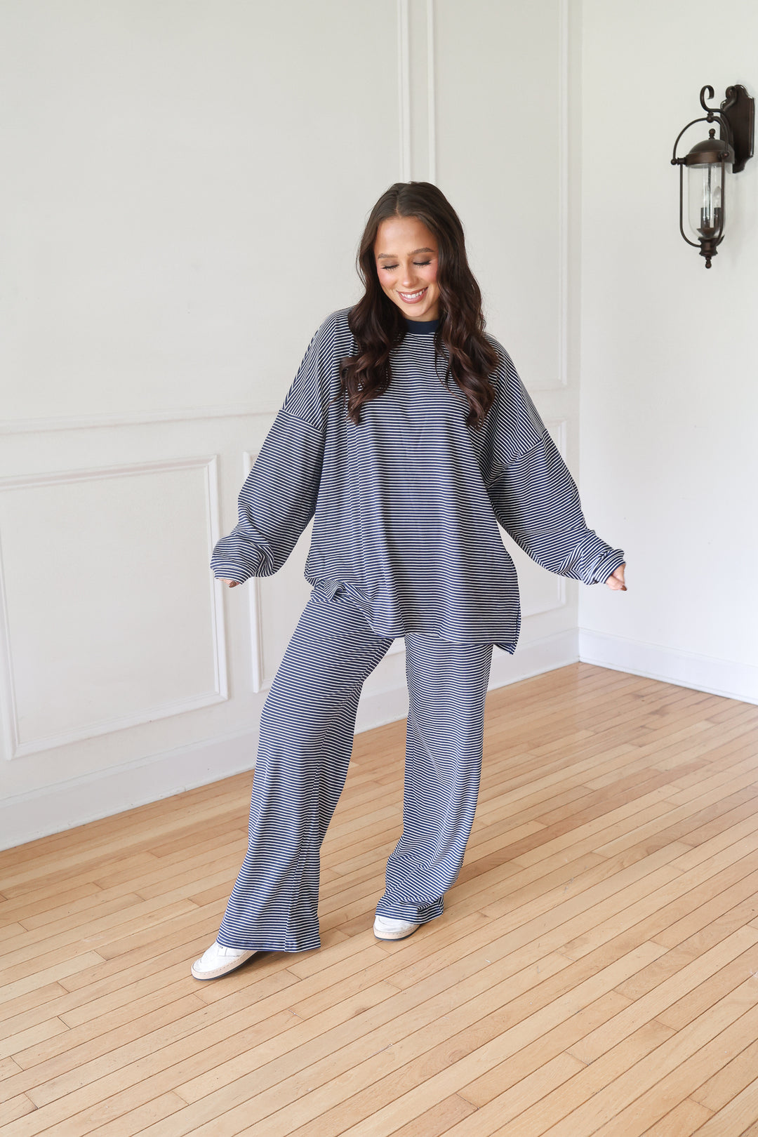 A woman modeling a matching navy knit lounge set consisting of a long-sleeve top and wide-leg pants