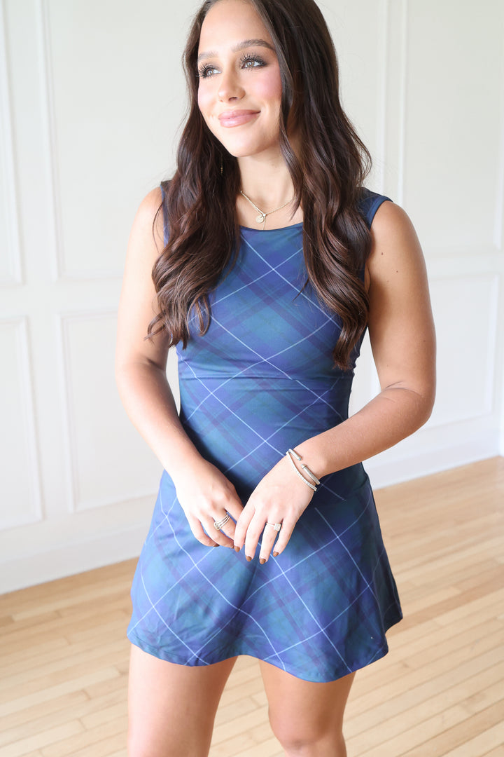 A woman modeling a sleeveless blue mini dress with a purple argyle pattern.