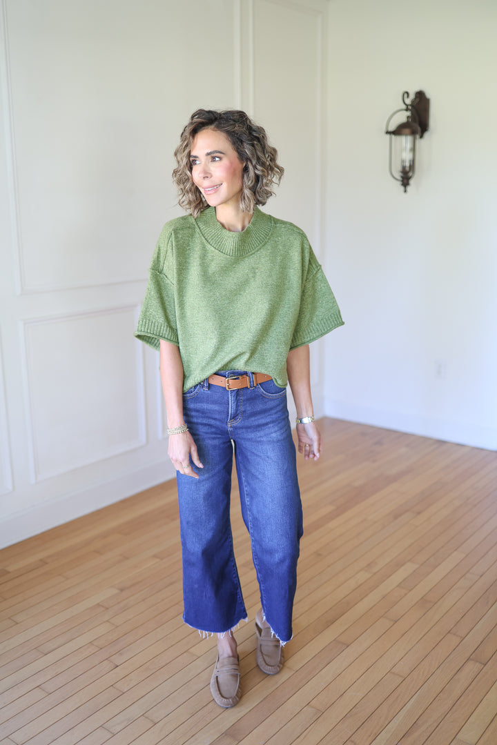 Woman wearing a green sweater and blue jeans 