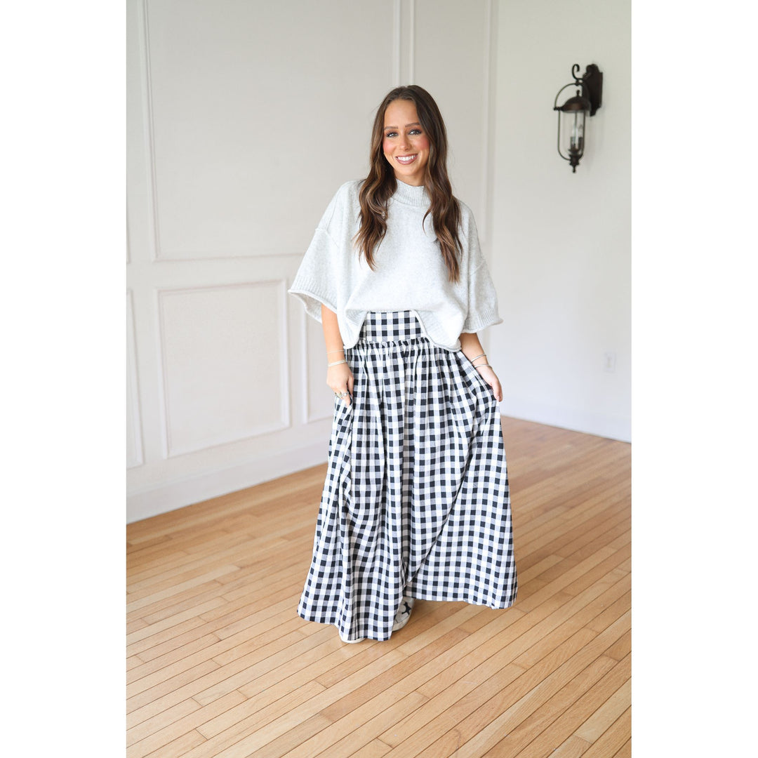 Woman wearing a gray top and black and white checkered skirt 