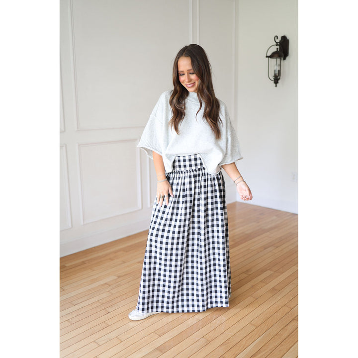 Woman wearing a white top and black and white checkered skirt 