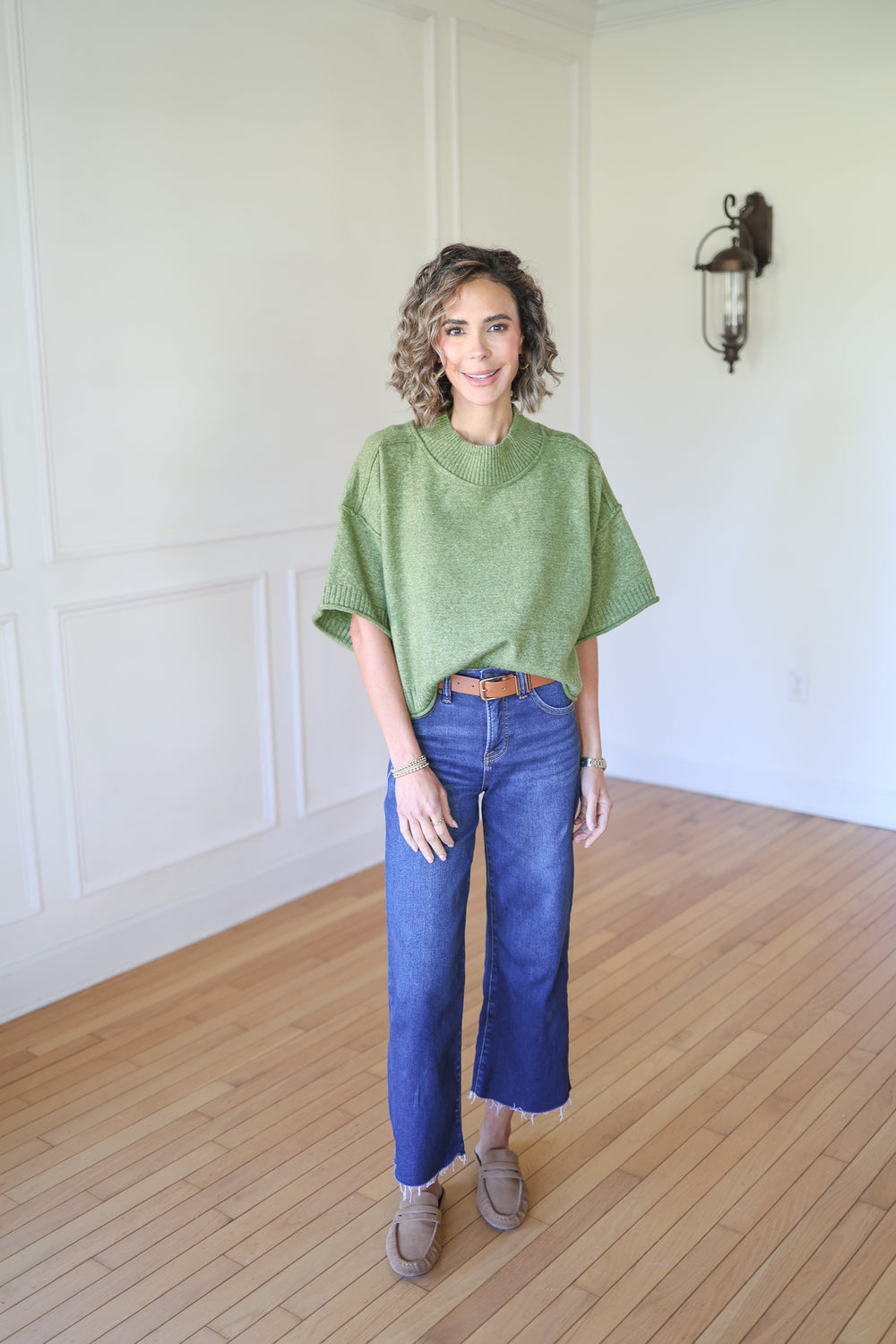 Woman wearing a green sweater and blue jeans 