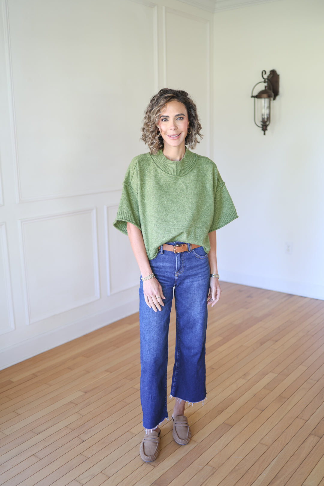 Woman wearing a green sweater and blue jeans 