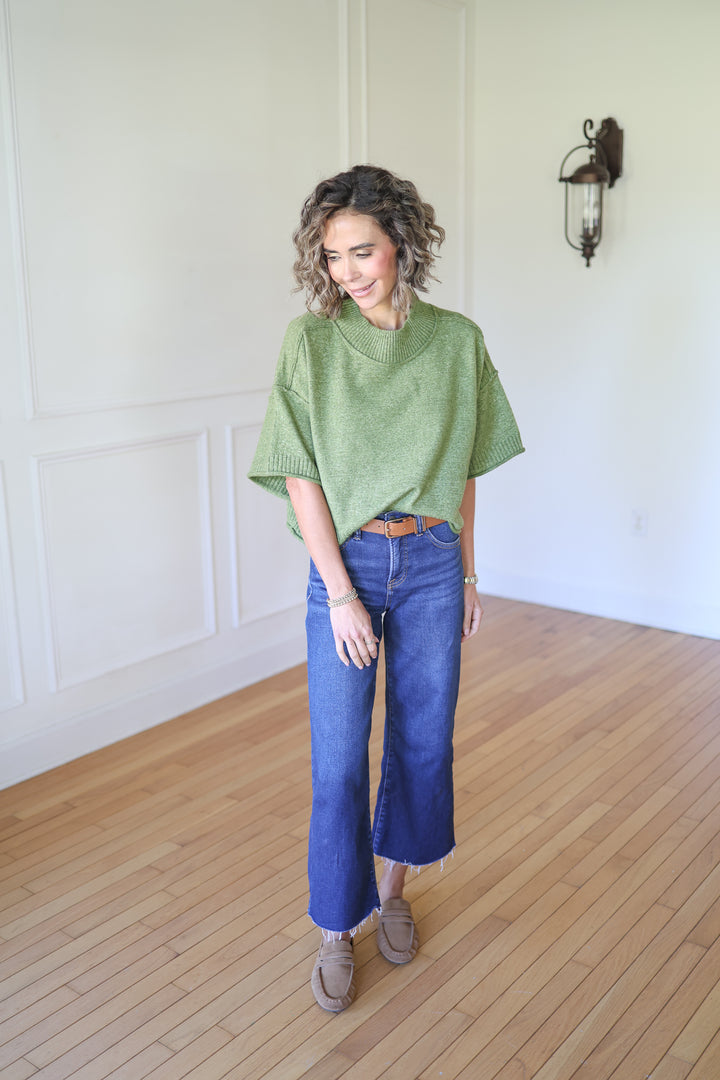 Woman wearing a green sweater and blue jeans 