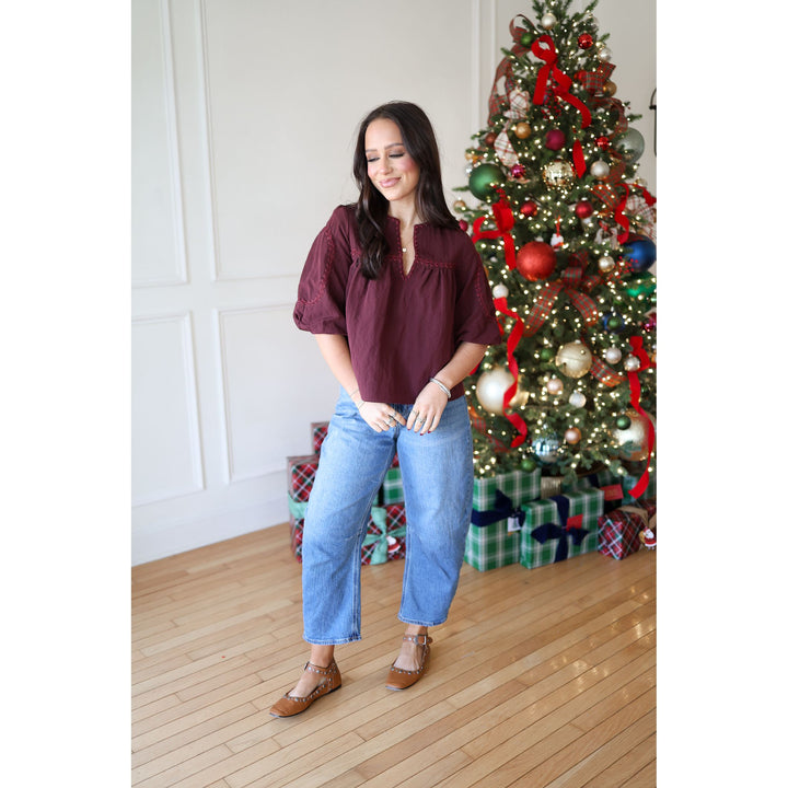 Woman standing in front of a decorated Christmas tree with presents underneath.