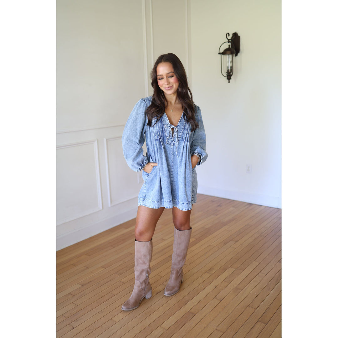 Woman wearing a light blue dress and beige knee-high boots 
