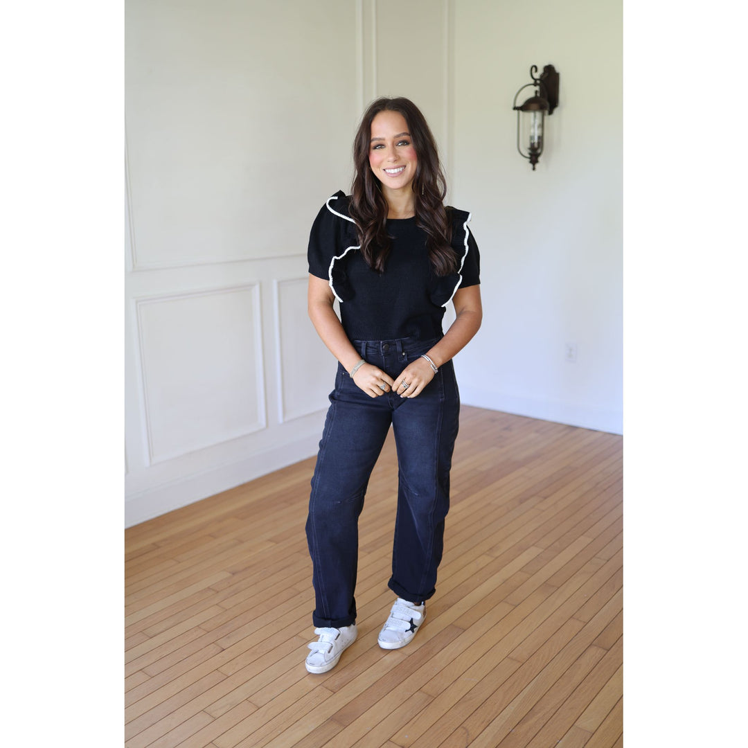 Woman wearing a black and white top and blue jeans 