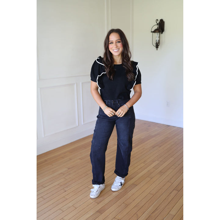 Woman wearing a black and white top and blue jeans 