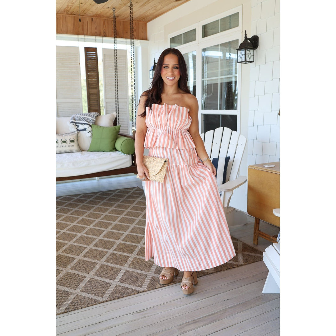 Woman in a pink striped set standing on a wooden deck.
