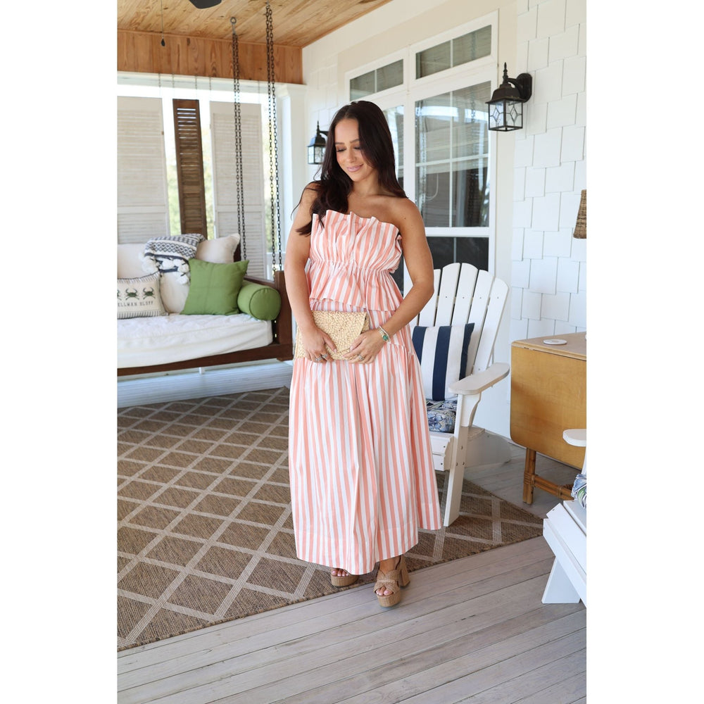Woman in a pink striped dress standing on a wooden deck.