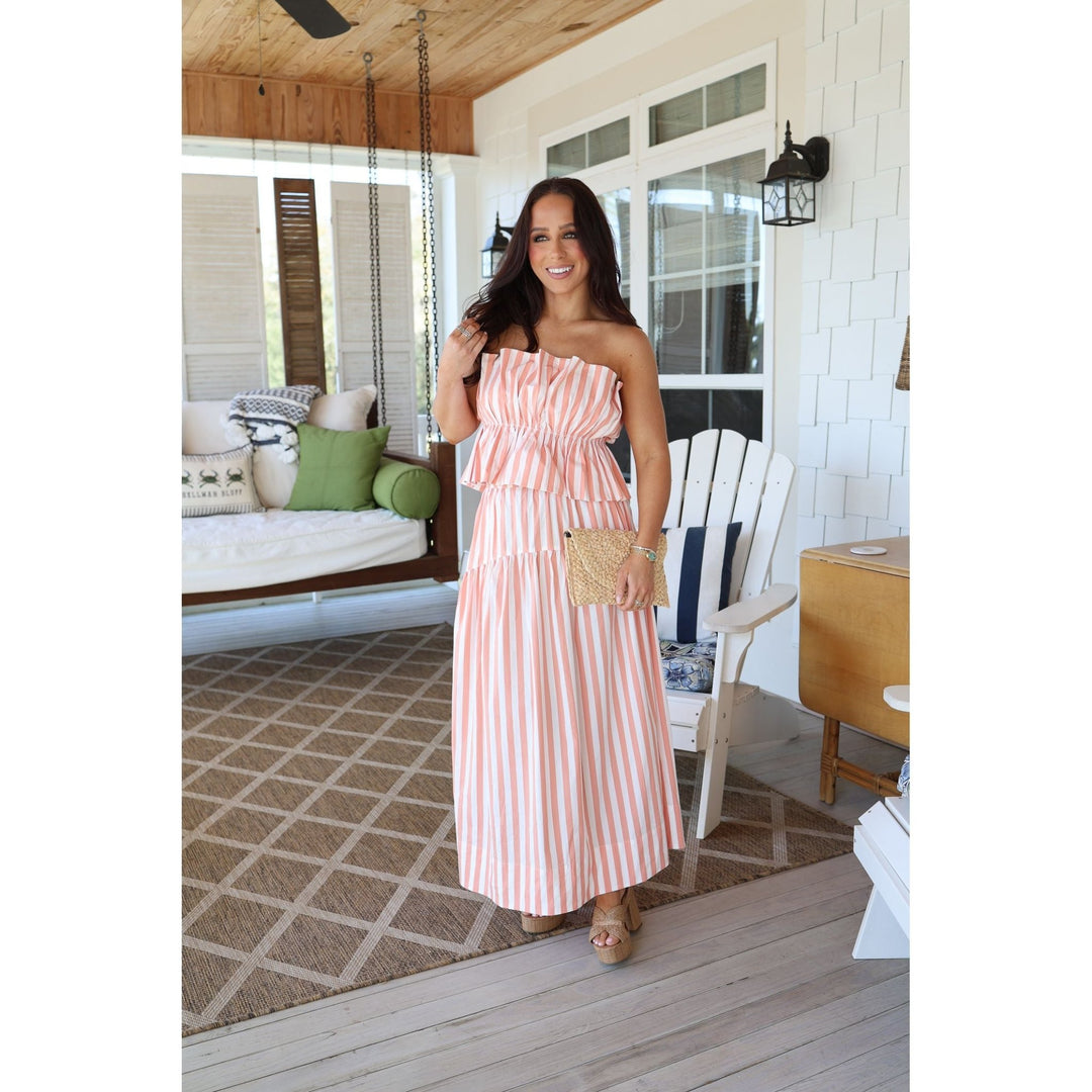 Woman in a pink striped set standing on a wooden deck.