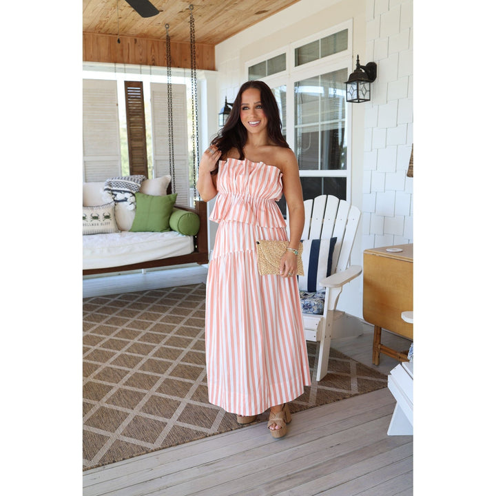 Woman in a pink striped set standing on a wooden deck.