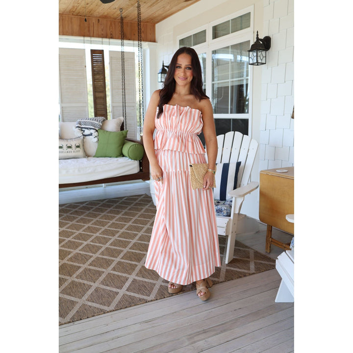 Woman in a pink striped set standing on a porch.