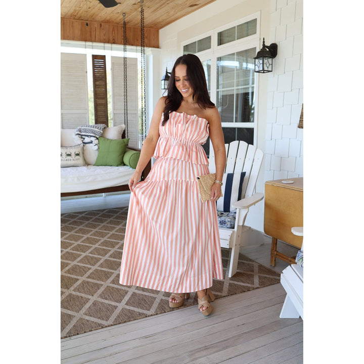 Woman in a pink striped set standing on a wooden deck.