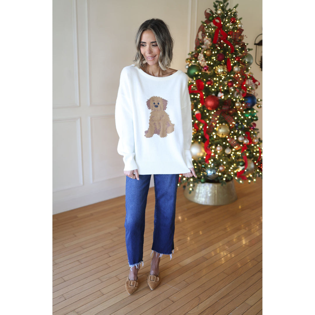 Woman wearing a white sweater with a teddy bear design in front of a decorated Christmas tree.
