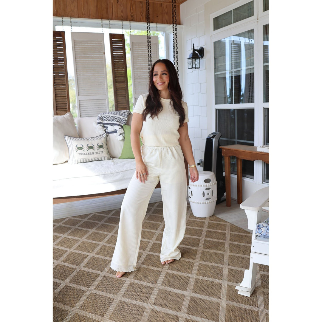 Woman in a white outfit standing on a patterned rug in a home setting.