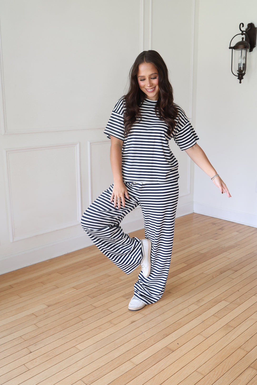 A woman modeling a matching two-piece loungewear set consisting of a short-sleeve crewneck top and wide-leg pants, both in a navy and white horizontal stripe pattern
