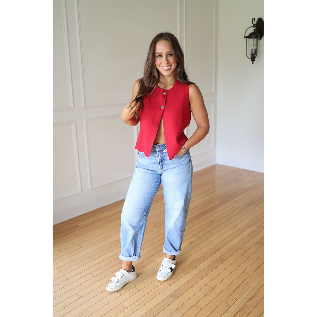 Woman wearing a red vest with light blue jeans