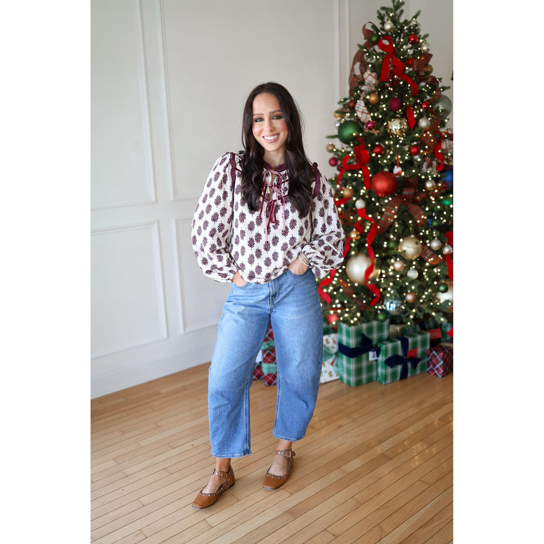 Woman standing in front of a decorated Christmas tree with presents underneath.