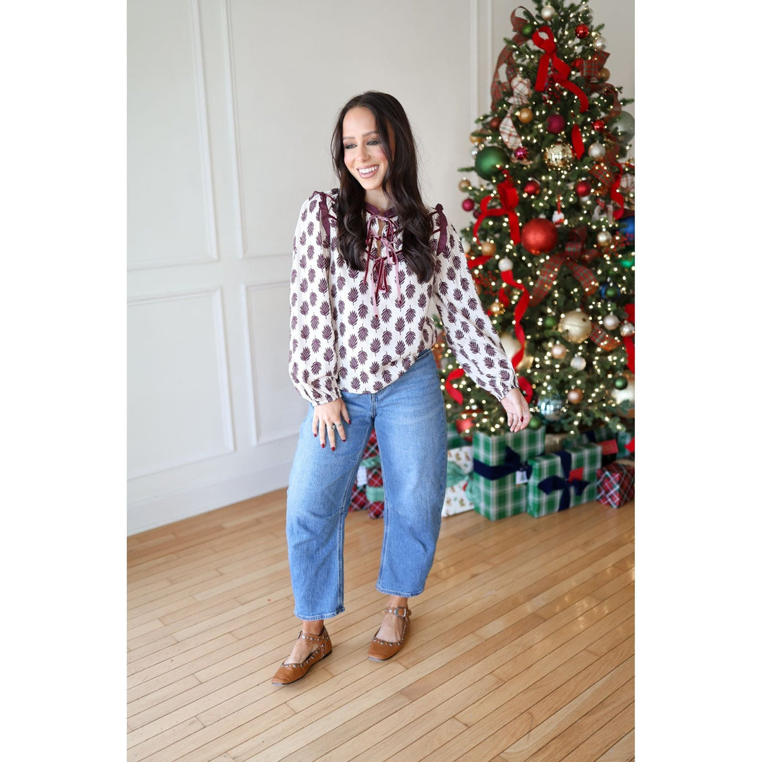 Woman standing in front of a decorated Christmas tree with a white wall background