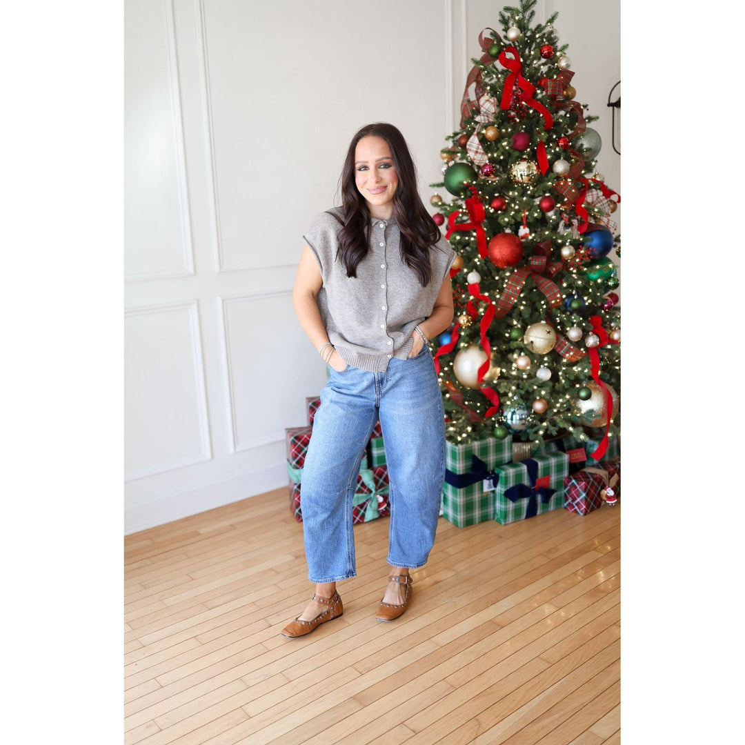 Woman standing in front of a decorated Christmas tree with presents underneath.