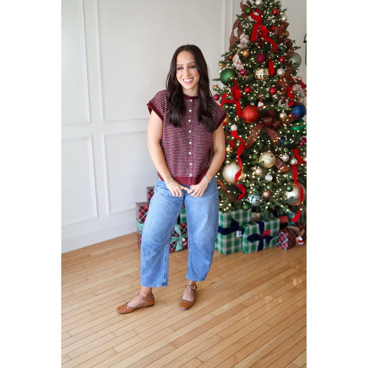 Woman standing in front of a decorated Christmas tree indoors.