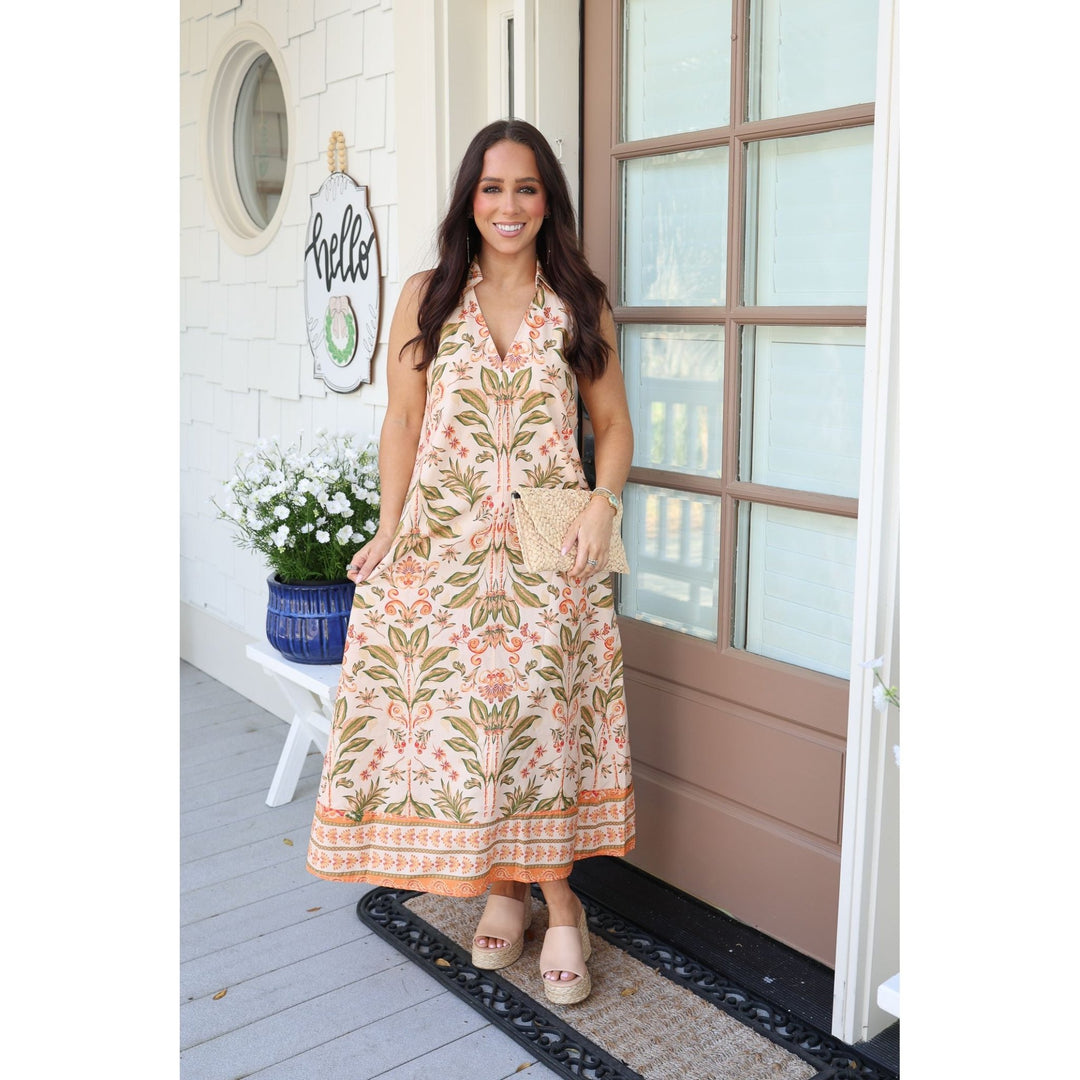 Woman in a floral dress standing on a porch 
