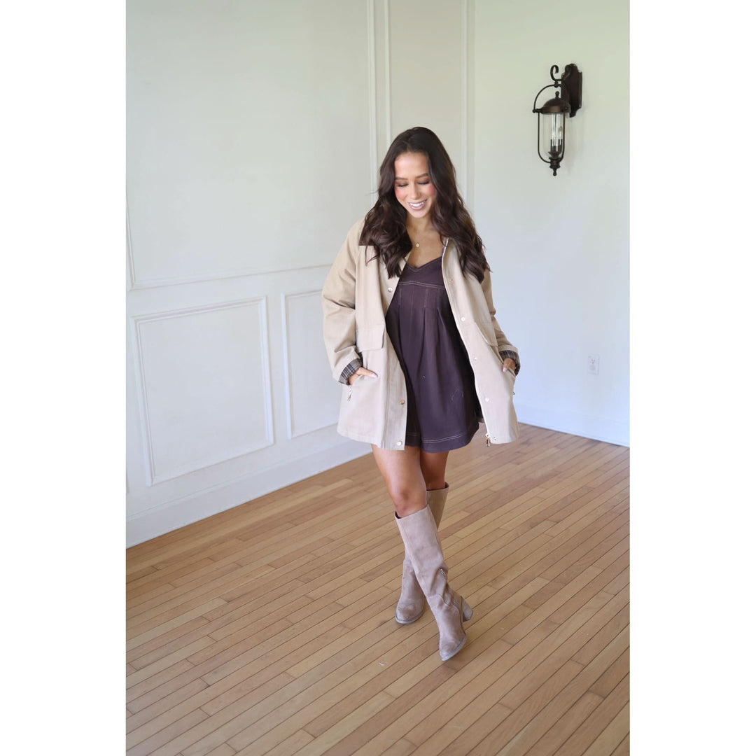 Woman in a beige coat and brown dress 