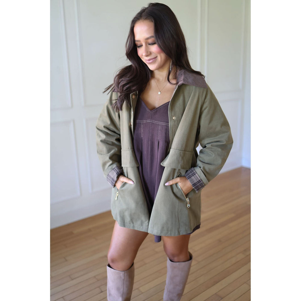 Woman wearing a green coat over a dress with knee-high boots 