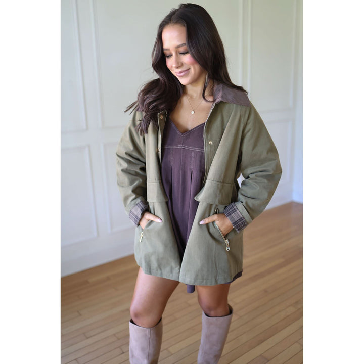 Woman wearing a green coat over a dress with knee-high boots 