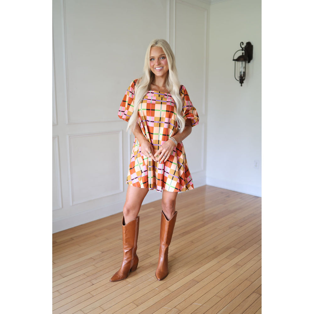 Woman wearing a plaid dress and brown boots 