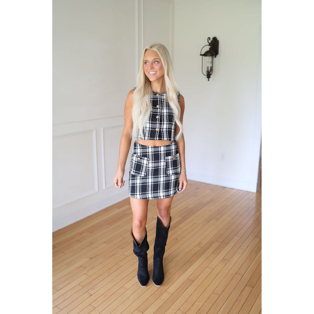 Woman wearing a black and white plaid set with black boots 