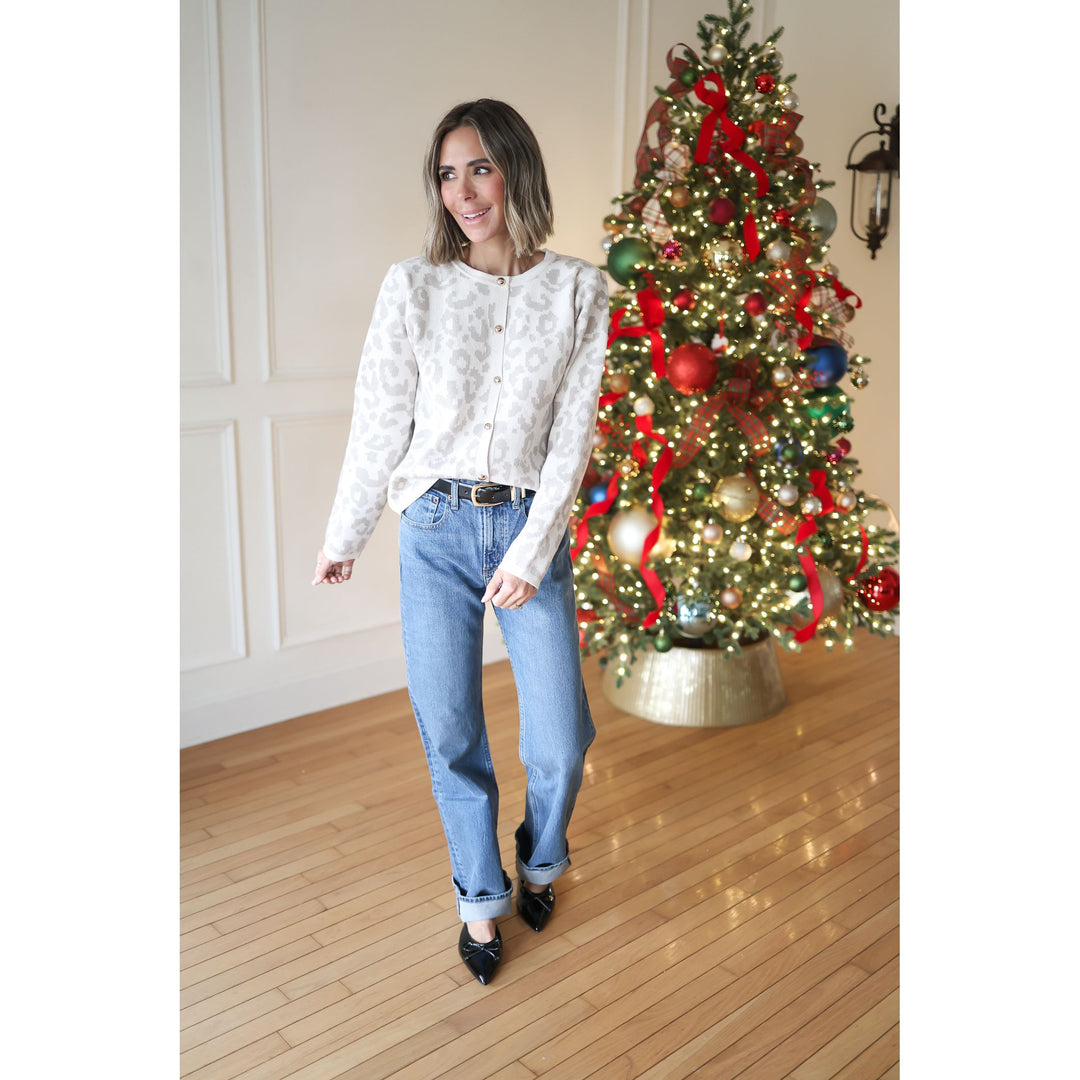 Woman standing next to a decorated Christmas tree indoors.