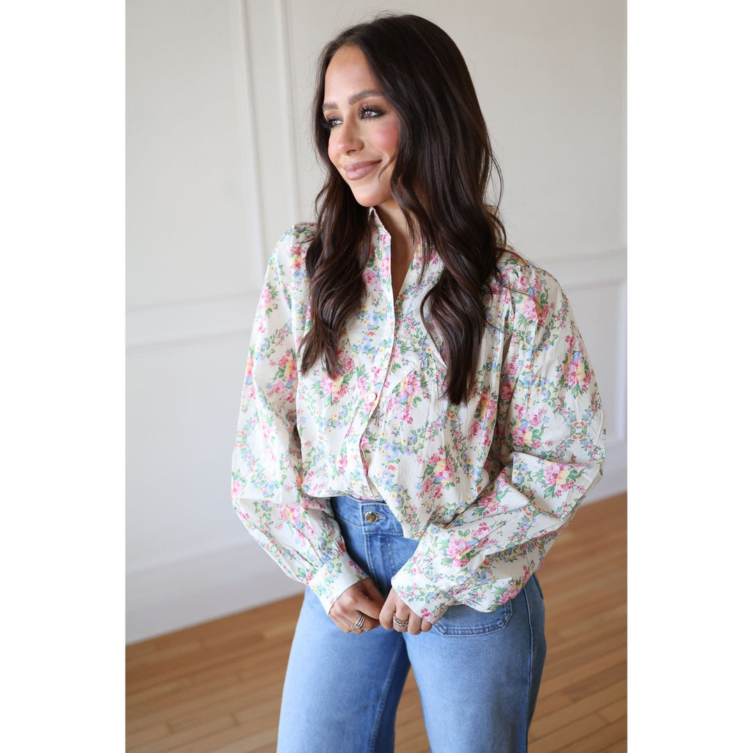 Woman wearing a floral blouse and jeans indoors