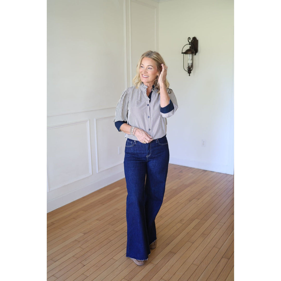 Woman wearing a striped shirt with rolled-up sleeves and dark blue jeans 