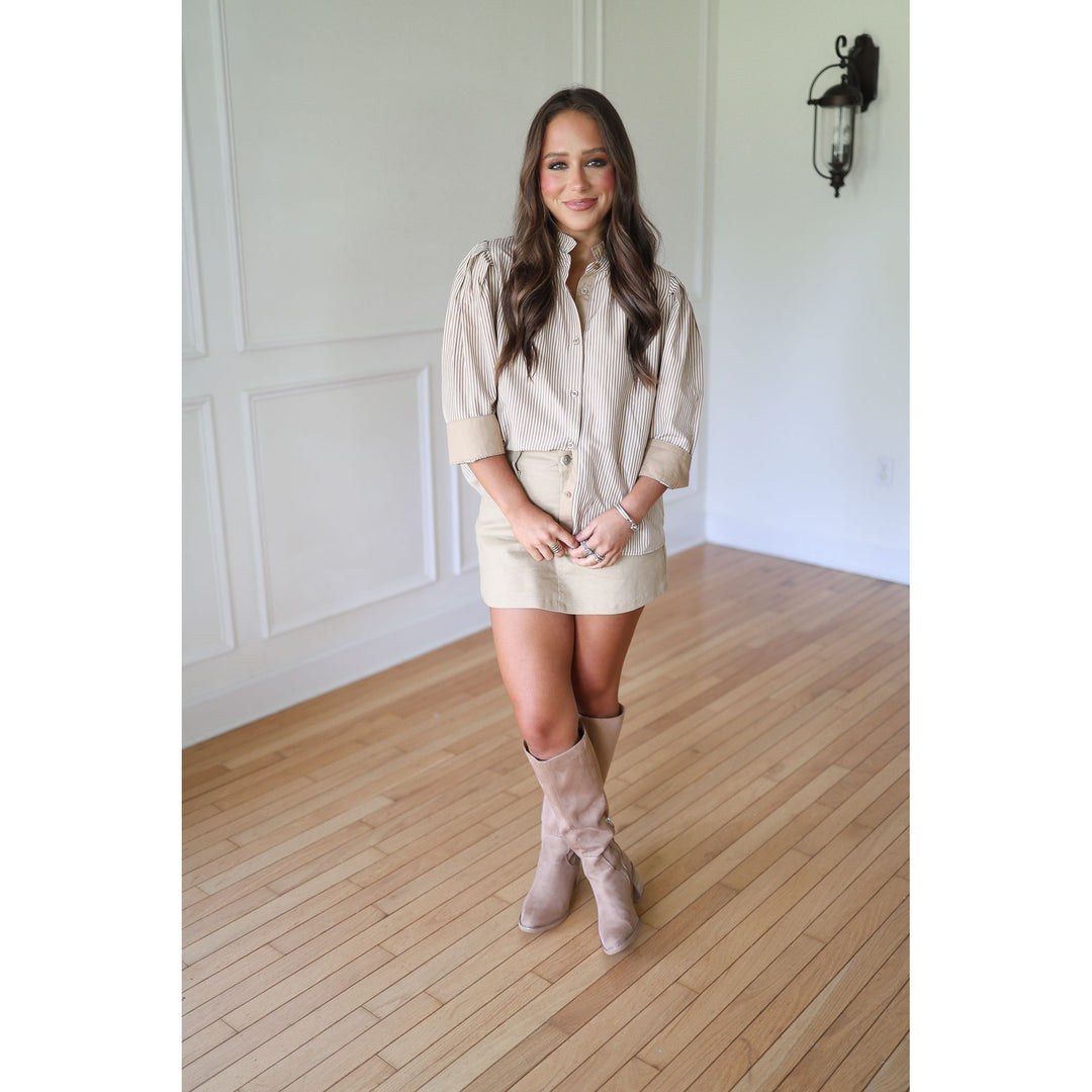 Woman wearing a beige shirt dress and boots 
