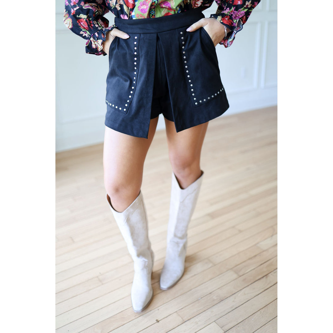 Person wearing black shorts with white buttons and floral top 