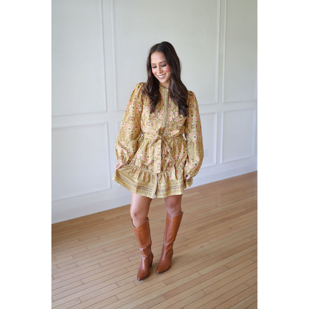 Woman wearing a gold floral dress and brown knee-high boots 