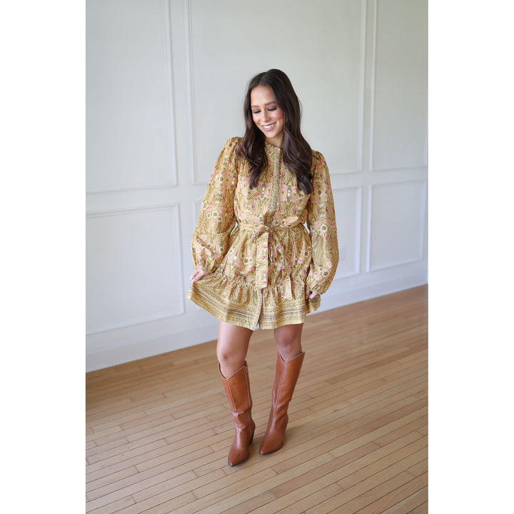 Woman wearing a gold floral dress and brown knee-high boots 