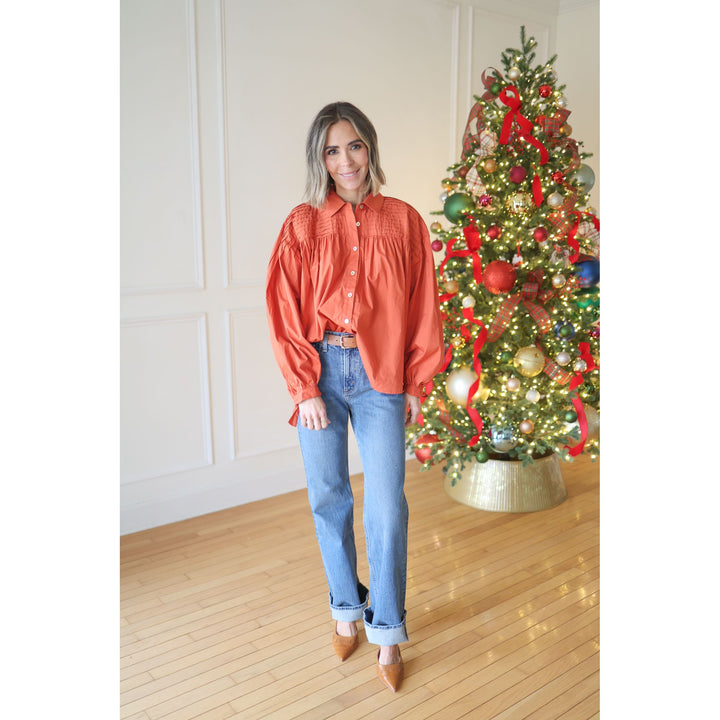 woman wearing rust blouse and jeans