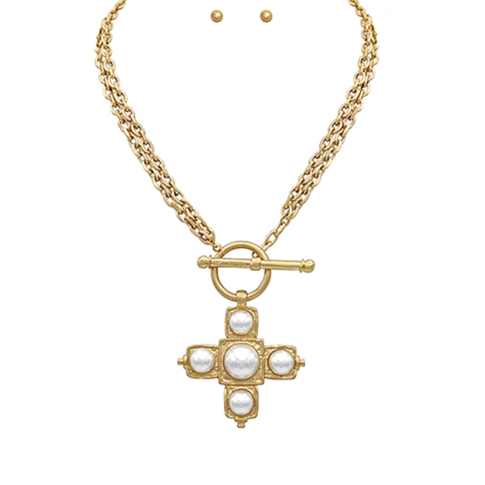 Gold cross pendant necklace with white pearl-like beads and a toggle clasp, with matching stud earrings.
