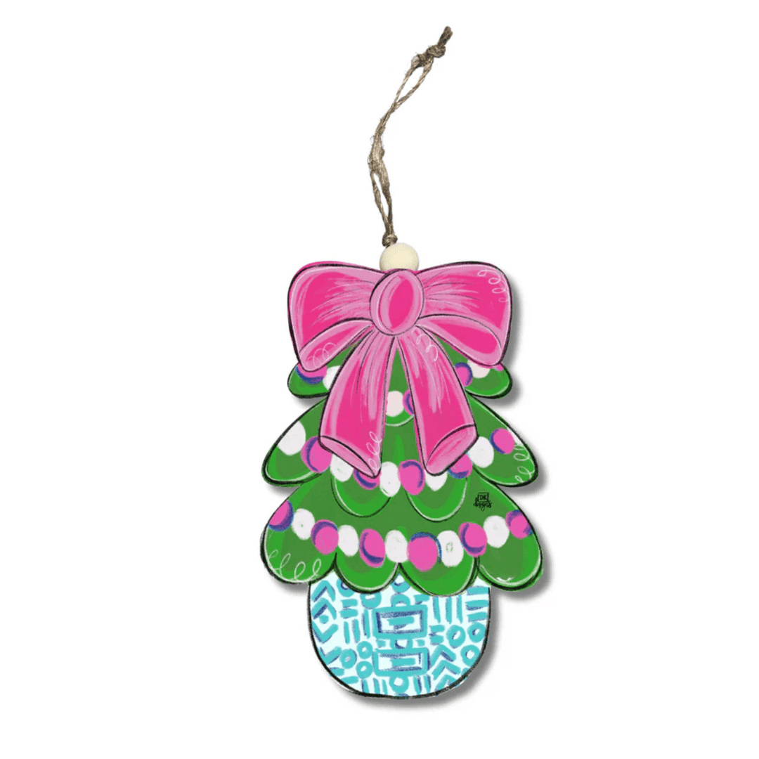 Decorative ornament with a pink bow, green tree design, and blue base on a white background