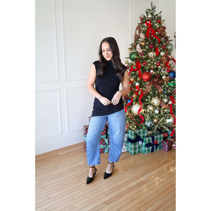 Woman standing in front of a decorated Christmas tree with presents underneath.