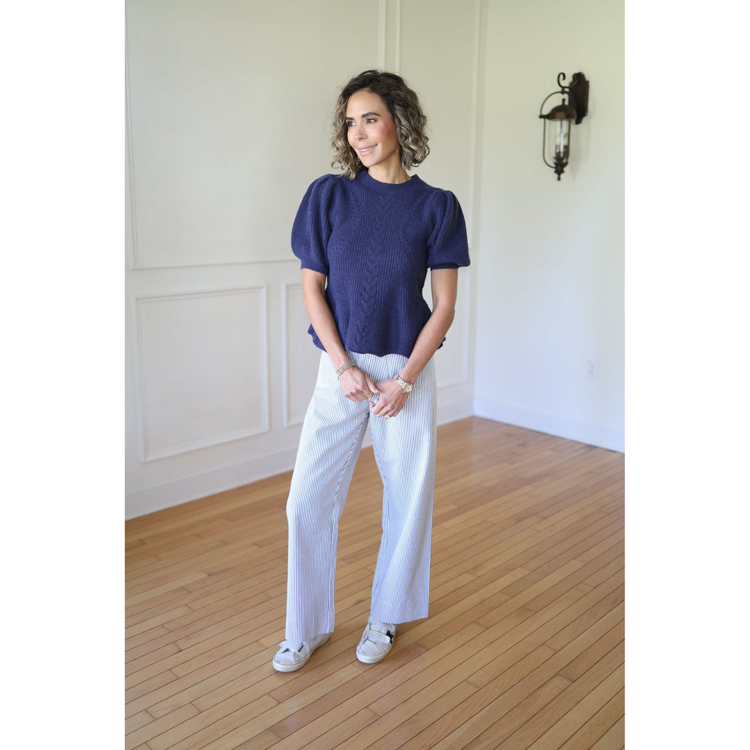 Woman wearing a navy blue top and white pants 