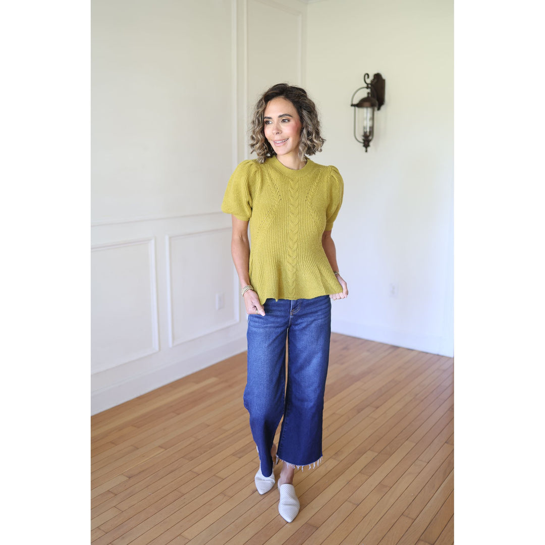 Woman wearing a green knitted top and blue jeans 