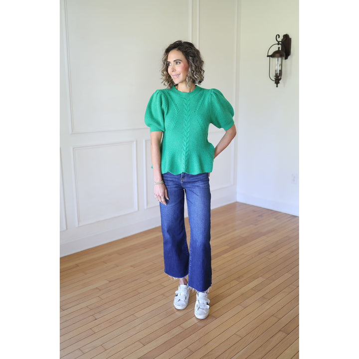 Woman wearing a green knitted top and blue jeans 