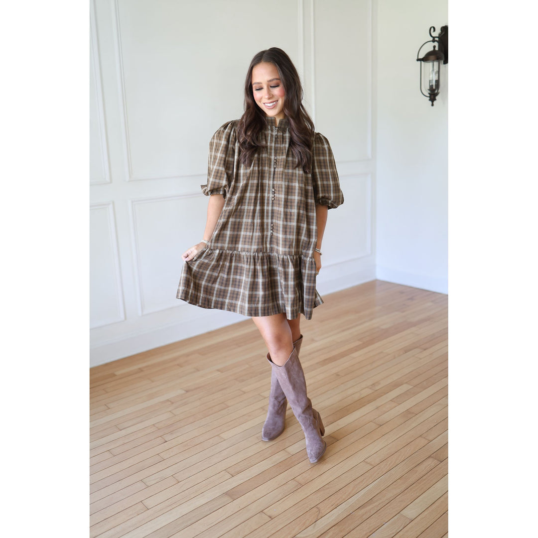 Woman wearing a plaid dress and gray knee-high boots